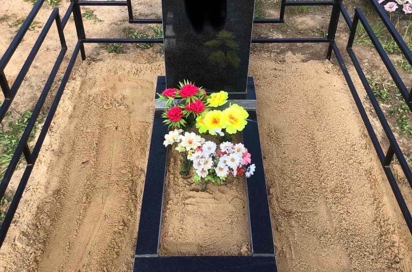 Подсыпали песком могилу на кладбище.